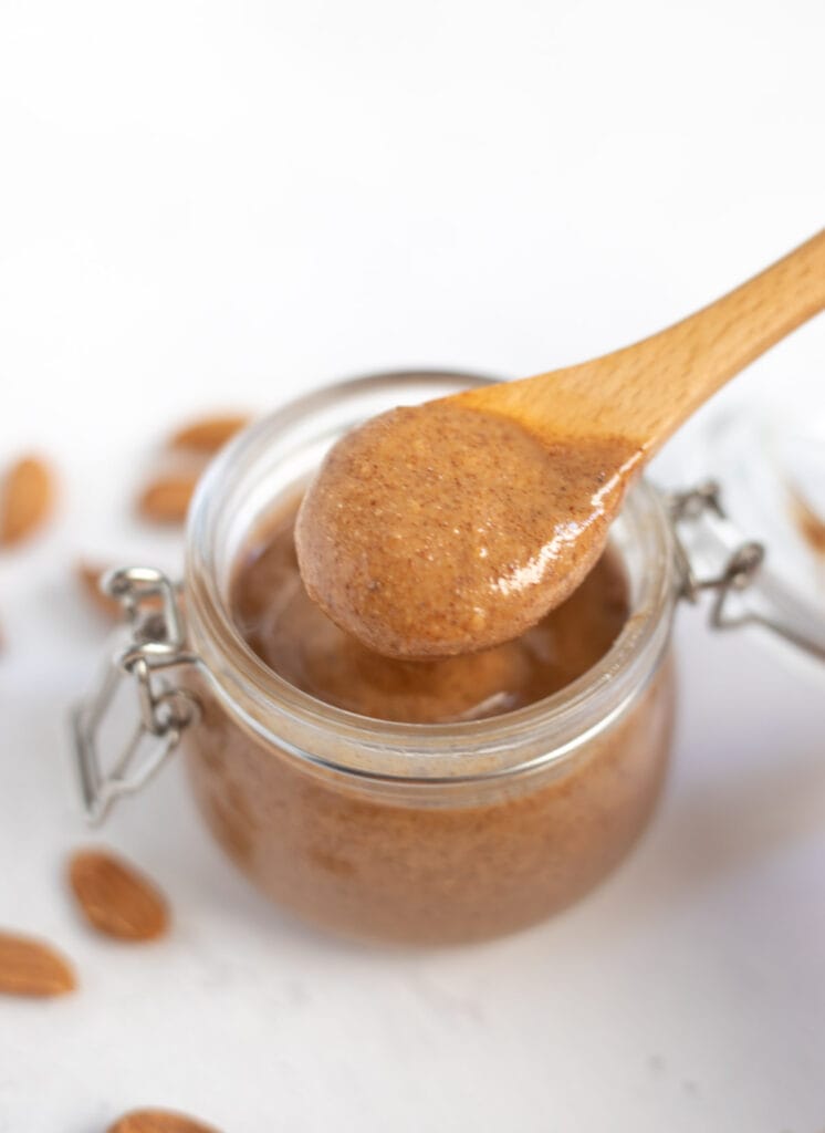 creamy almond butter spooned out from a glass jar
