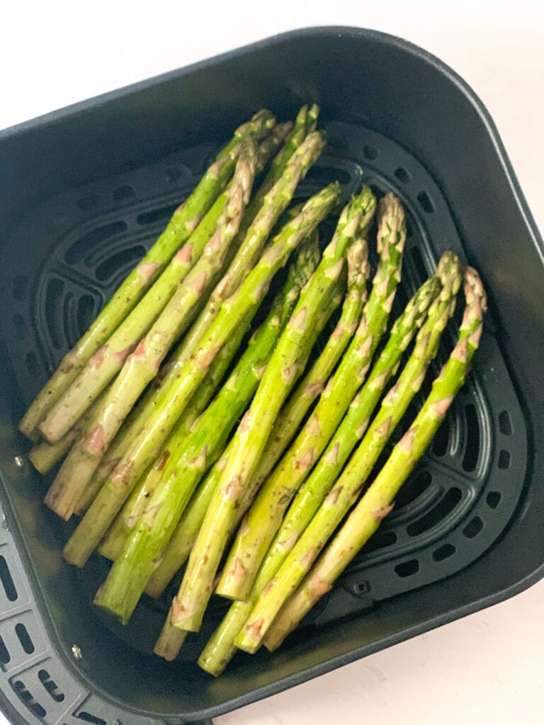 seasoned asparagus spears in the air fryer ready to be roasted