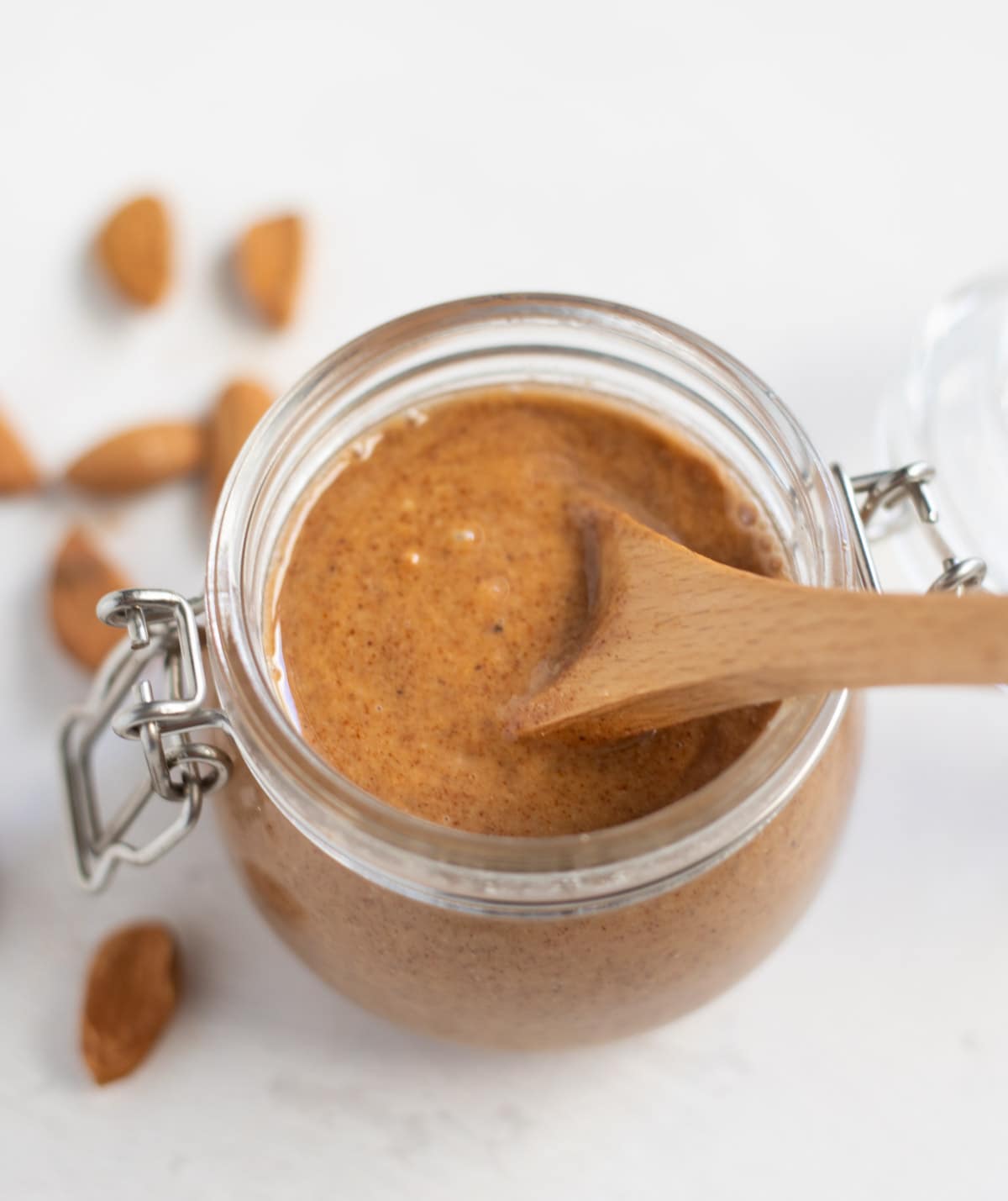 Almond butter in a glass jar with a wooden spoon