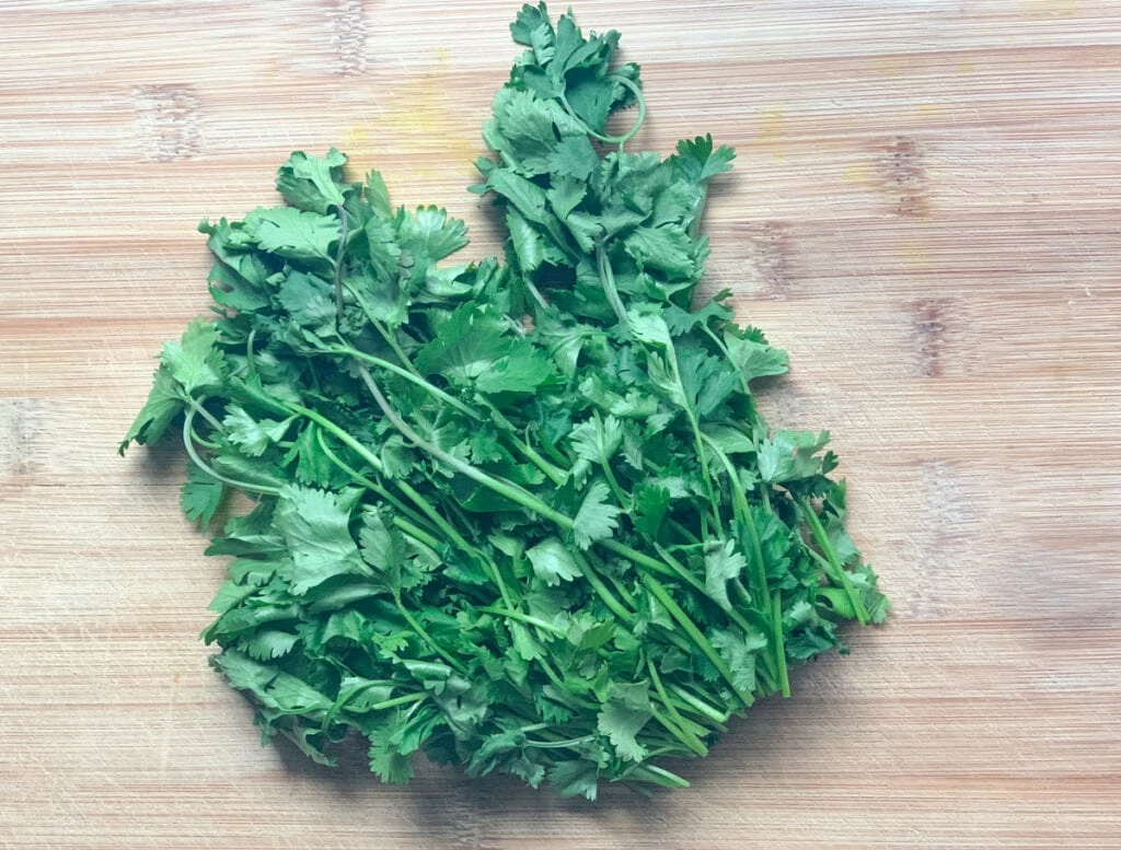 fresh cilantro on a wooden cutting board with stems removed