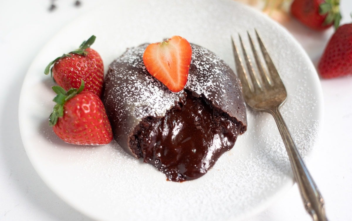 chocolate lava cake with chocolate flowing and strawberry in the top and side