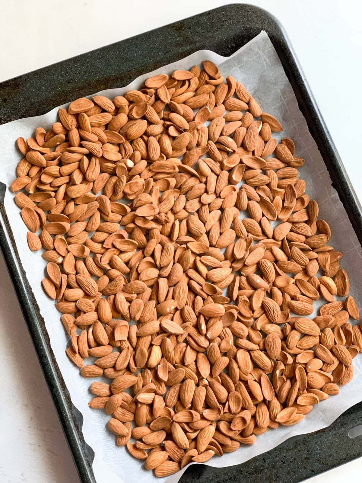 raw almonds on a baking sheet with parchment paper