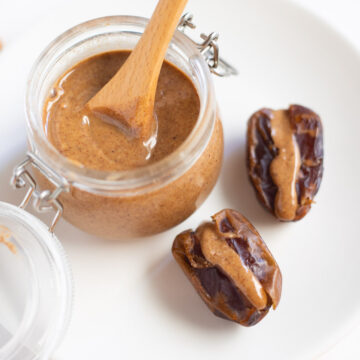 homemade almond butter in glass jar on white plate with dates