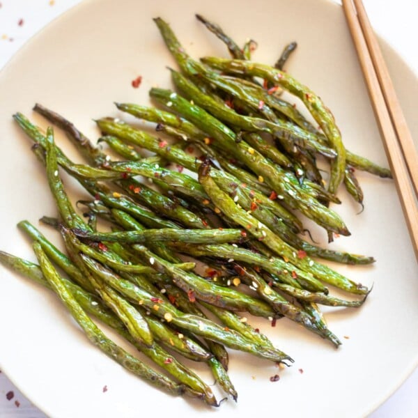 Chinese style roasted green beans with garlic on a plate with chopsticks