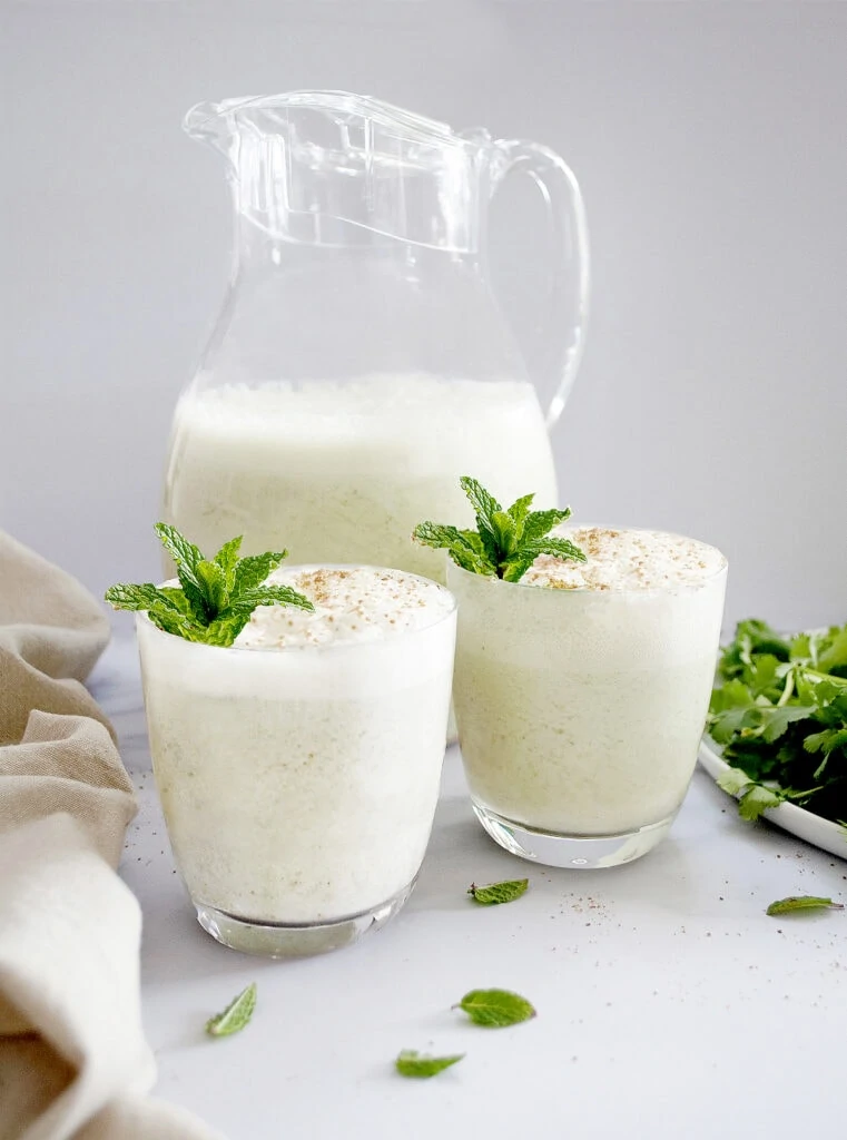 Indian Buttermilk Chaas in 2 glasses and a jug garnished with mint leaves