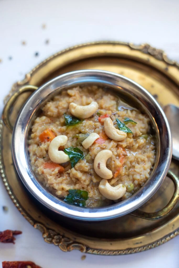Bisi Bele Bath - How Spicy lentils and rice in a pretty bowl garnished with tempering and cashews.