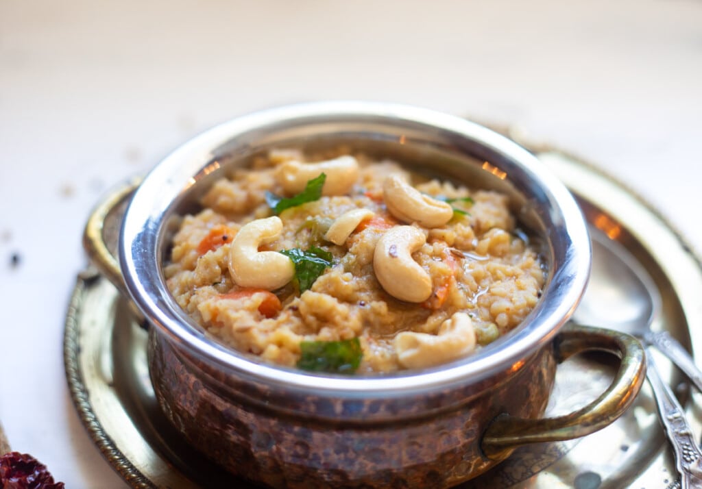 Bisi Bele Bath in a pretty serving bowl topped with tempering of cashews and curry leaves.