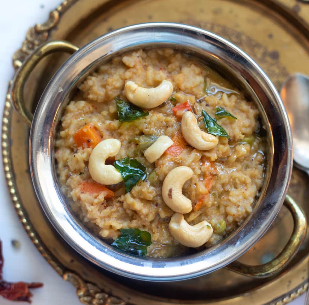 Bisi Bele Bath - How Spicy lentils and rice in a pretty bowl garnished with tempering and cashews.