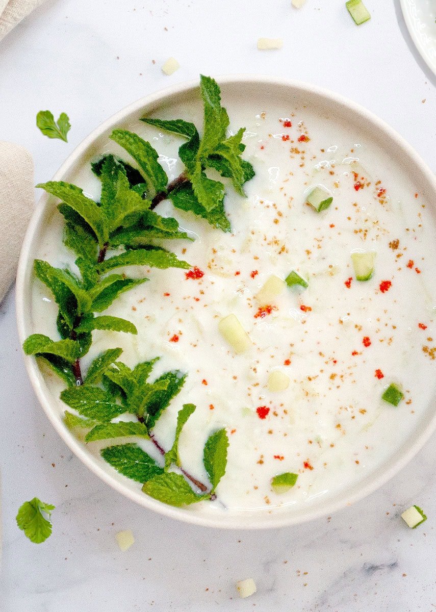 Indian Cucumber Raita in a bowl garnished with mint leaves and spices
