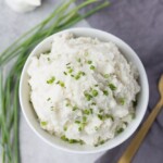 Vegan Mashed potato in a white bowl garnished with onion chives