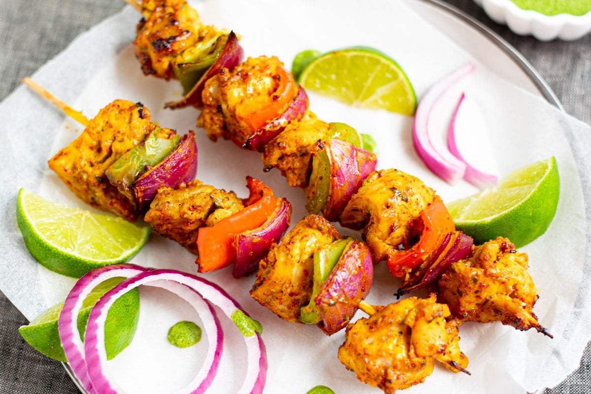 Chicken Tikka Kebab garnished with onions and green chutney on side