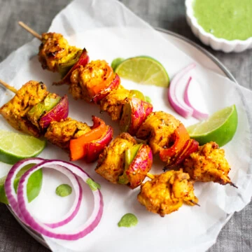 Chicken Tikka Kebab garnished with onions and green chutney on side