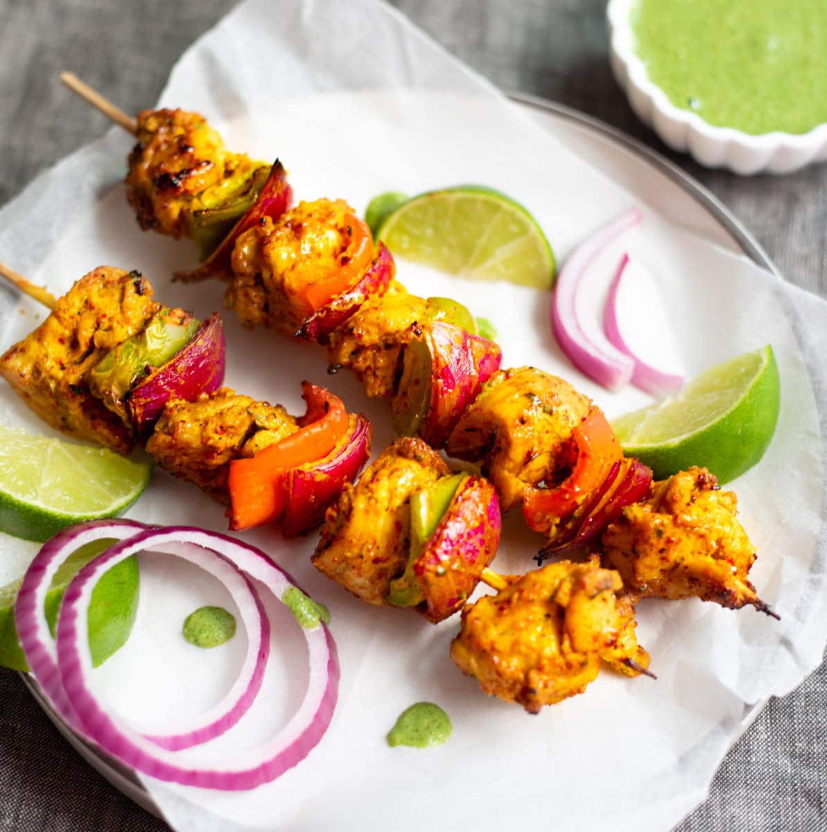 Chicken Tikka Kebab garnished with onions and green chutney on side