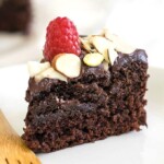 a slice of vegan chocolate cake topped with red berry and nuts
