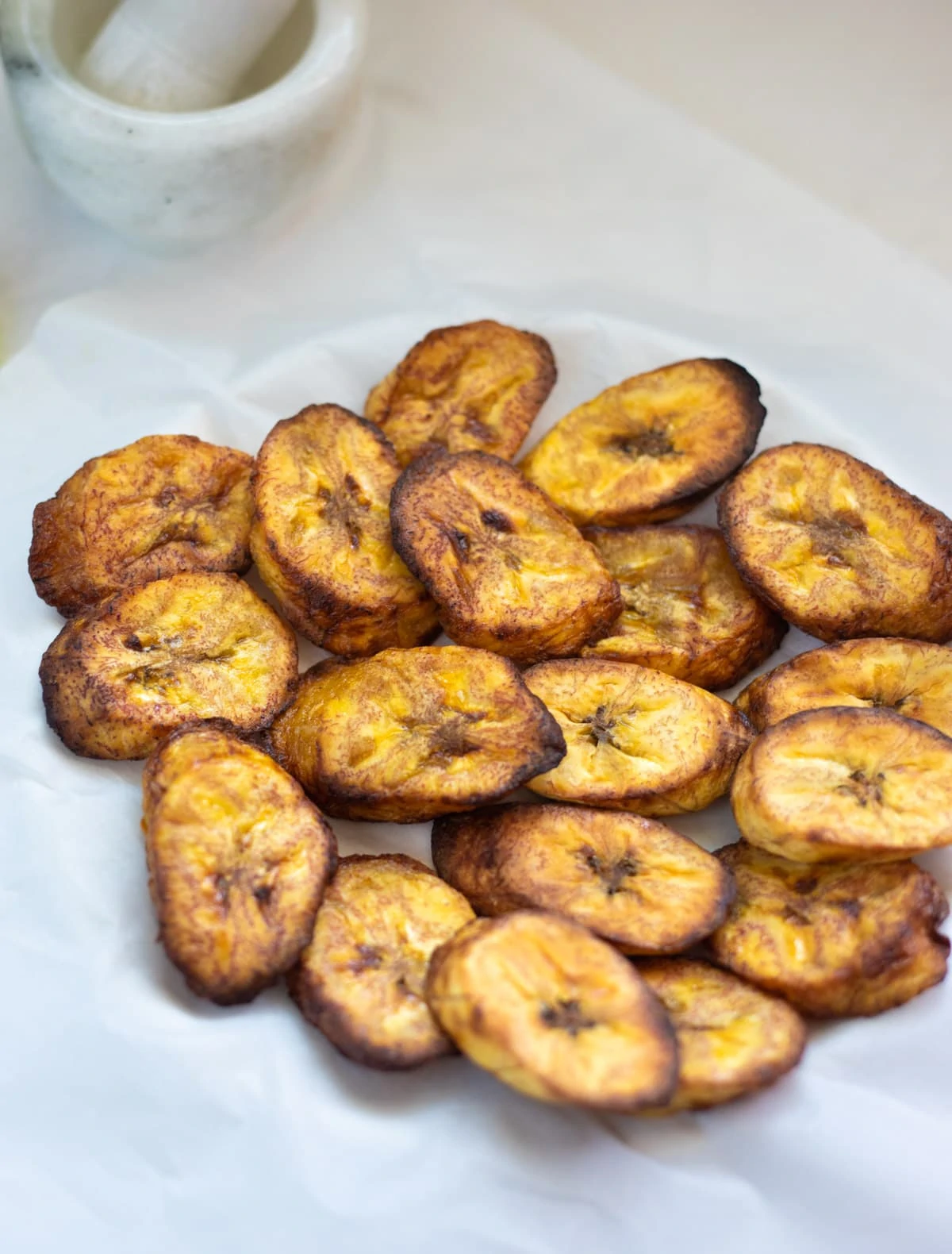 air fried plantains served in a plate over parchment paper 