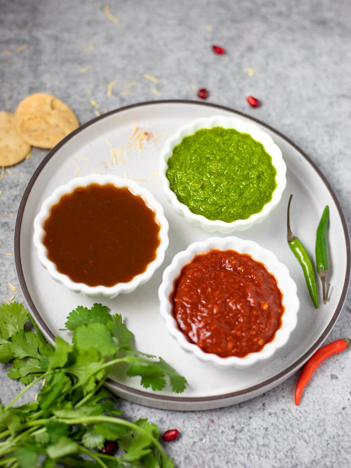 3 Indian dipping sauces in small bowls - green chutney, tamarind chutney, red chili garlic chutney