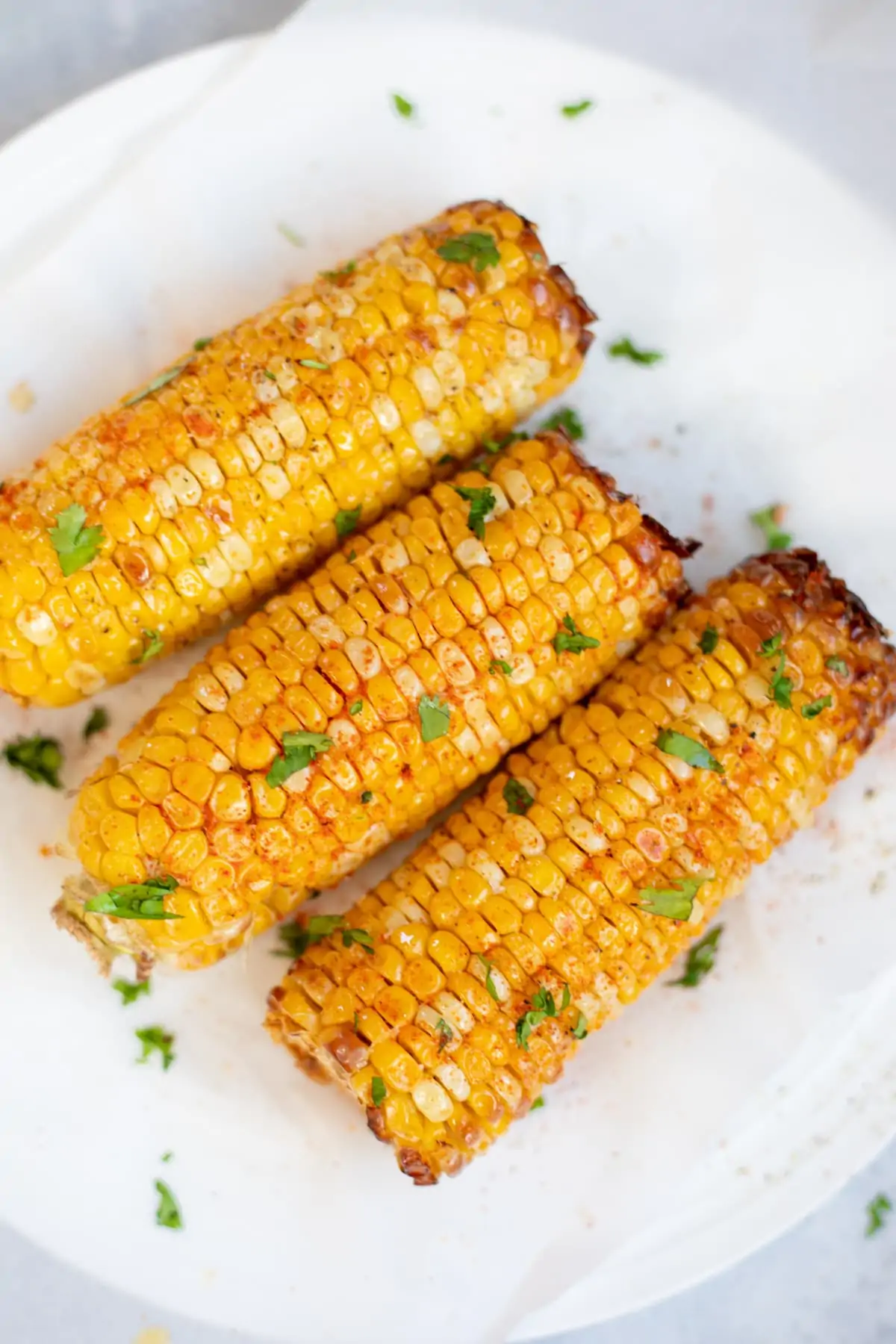 Spicy roasted corn on the Cobb on a plate garnished with cilantro