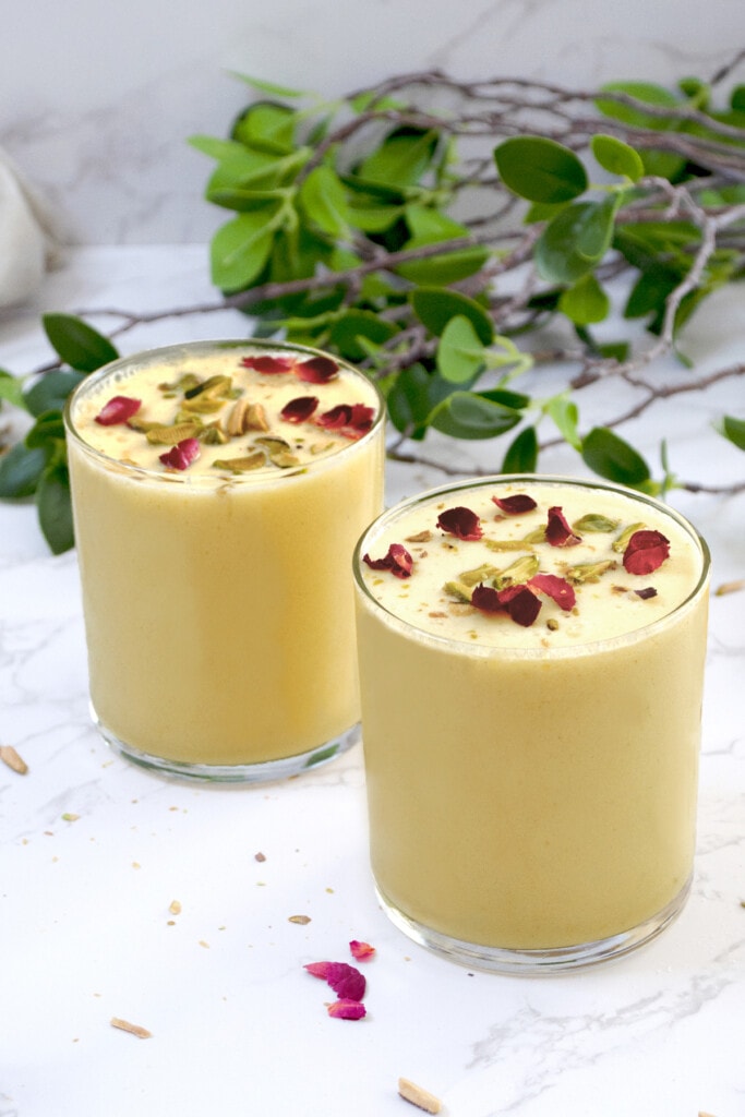 two glass of mango milk smoothie topped with petals