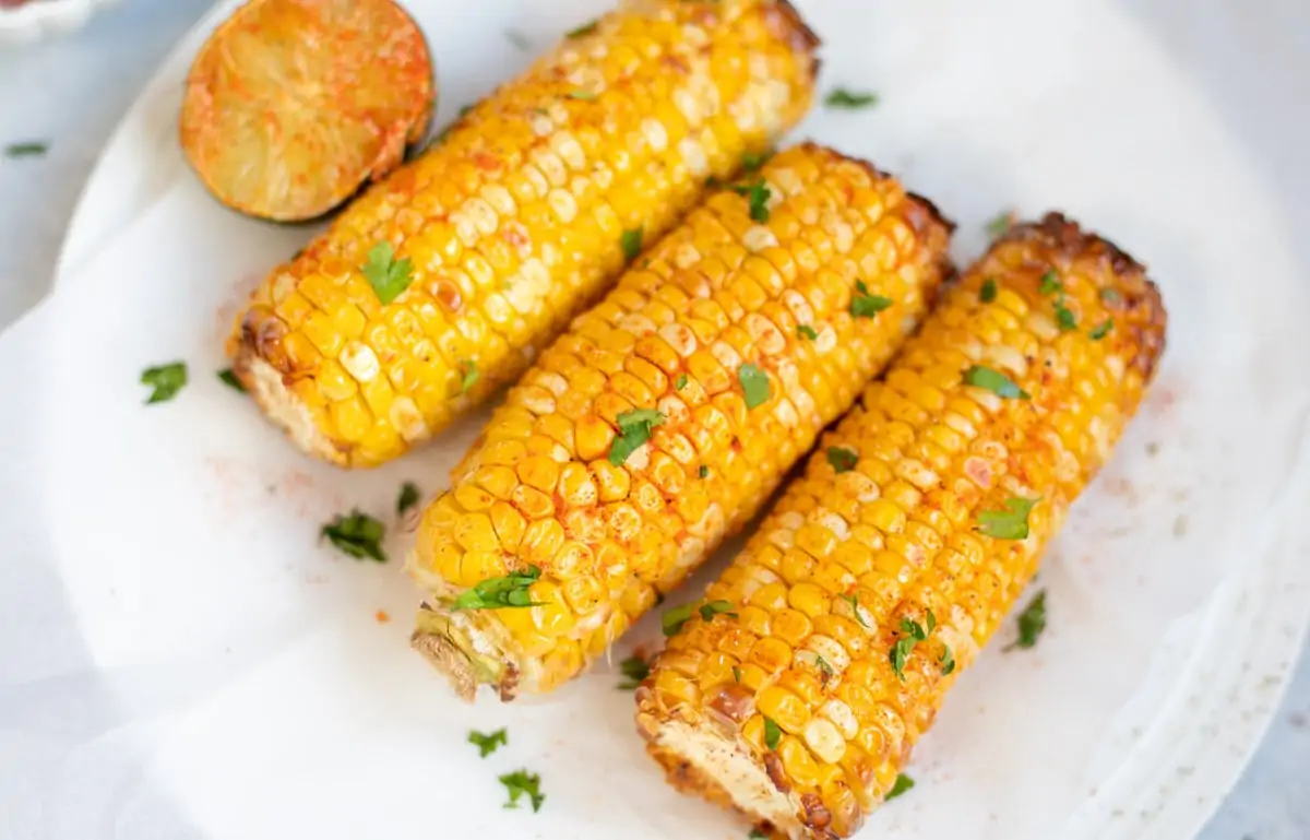 Spicy Corn on the cob served on a plate with a spiced lime on the side