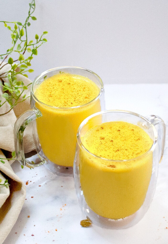 Turmeric Golden Milk Latter in 2 glass mugs placed on a marble counter