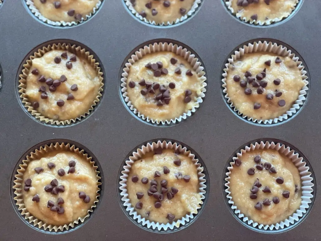 Muffin batter topped with chocolate chips in a muffin pan