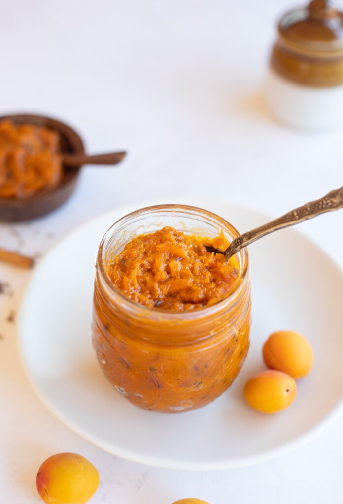 Apricot Chutney in a glass jar with some apricots spread around 