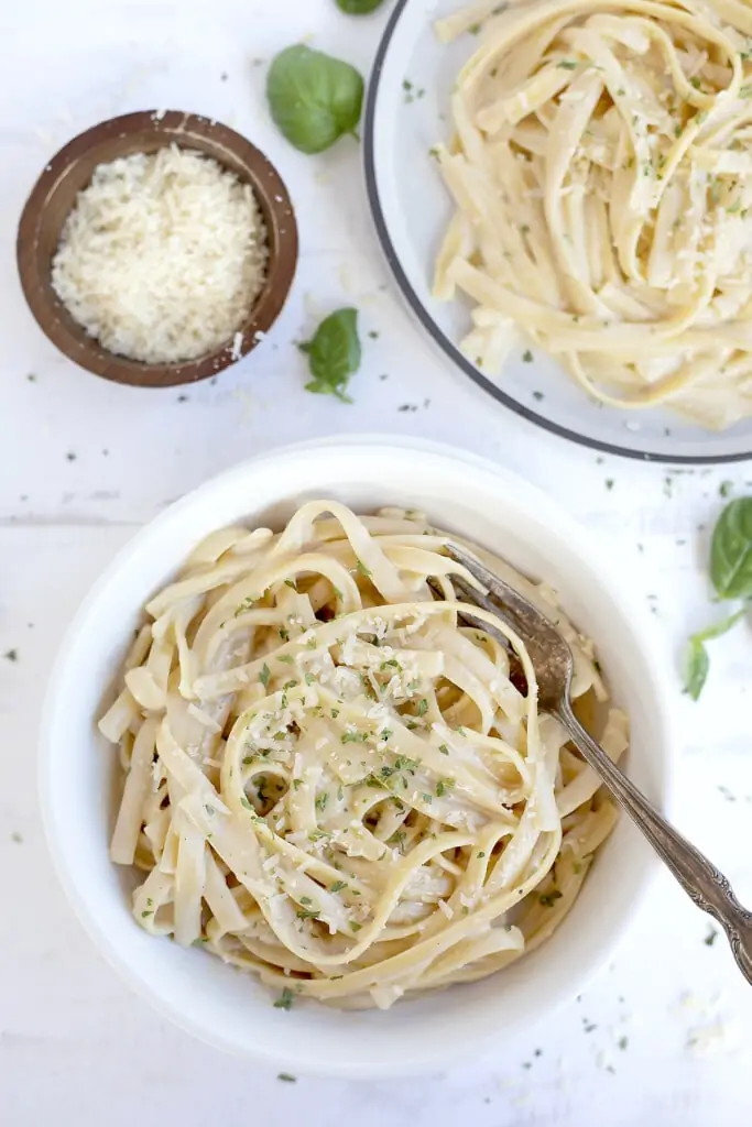Easy fettuccini Alfredo in a bowl served with parmesan on the top. 