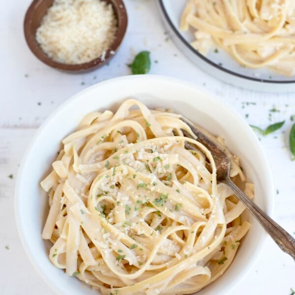 Creamy Fettucini Alfredo served in a bowl topped with parmesan and parsley