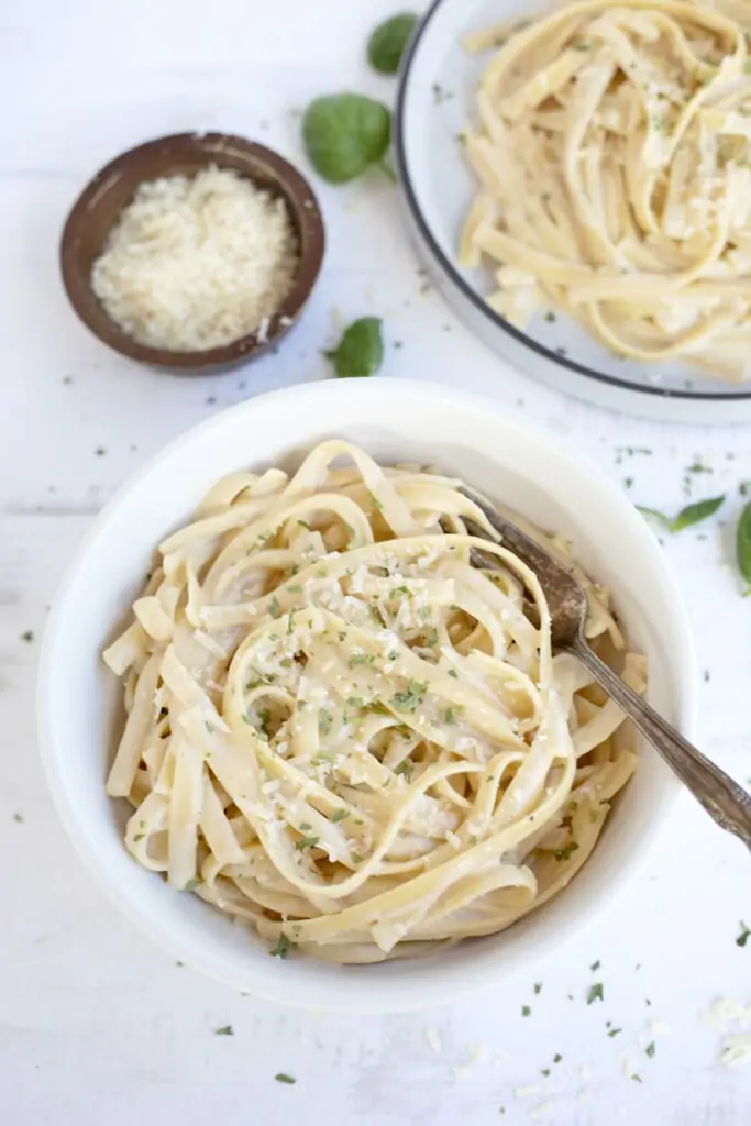 Creamy Fettucini Alfredo served in a bowl topped with parmesan and parsley 
