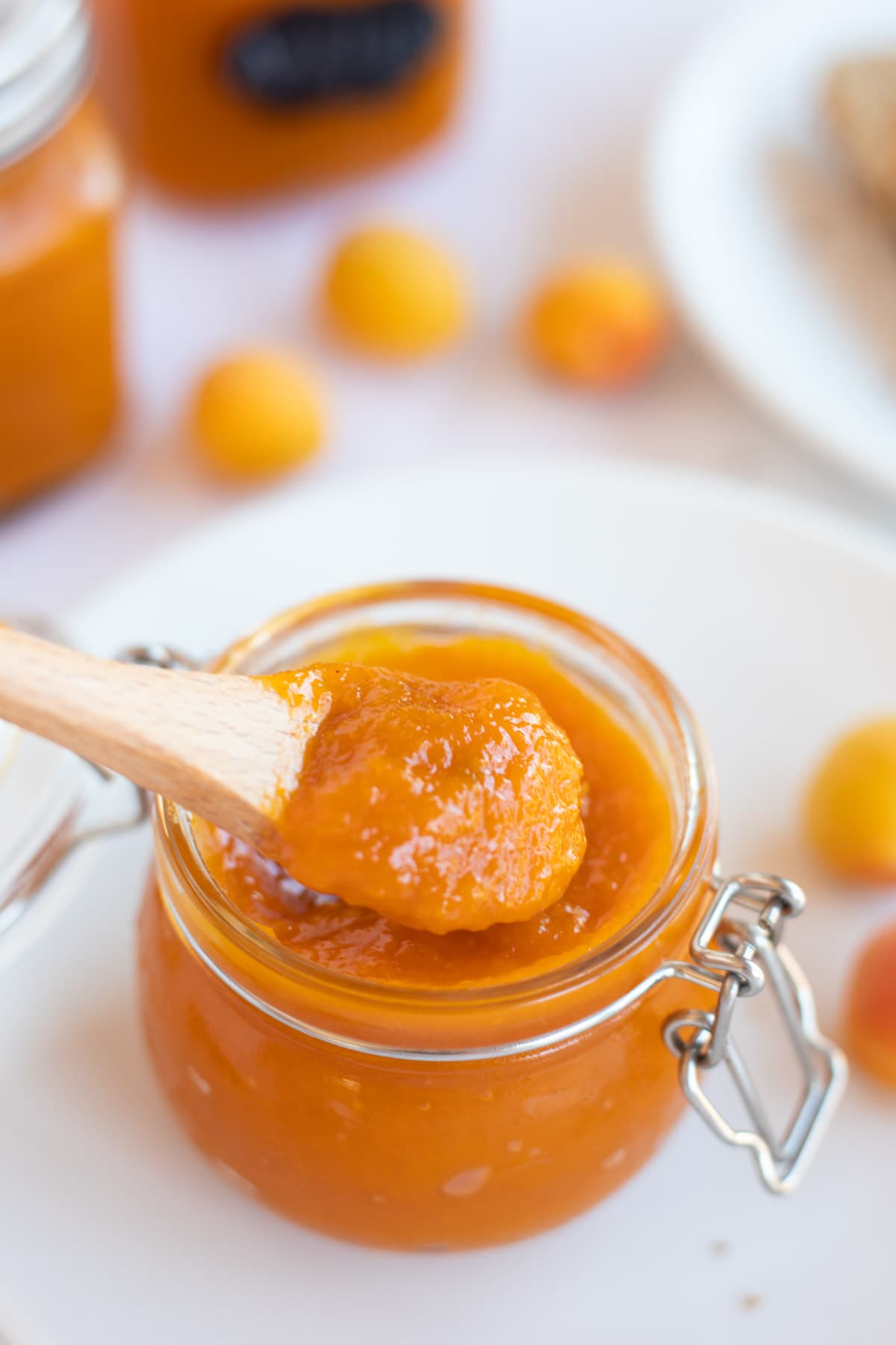 Delicious apricot jam being taken out from a glass mason jar by spoon