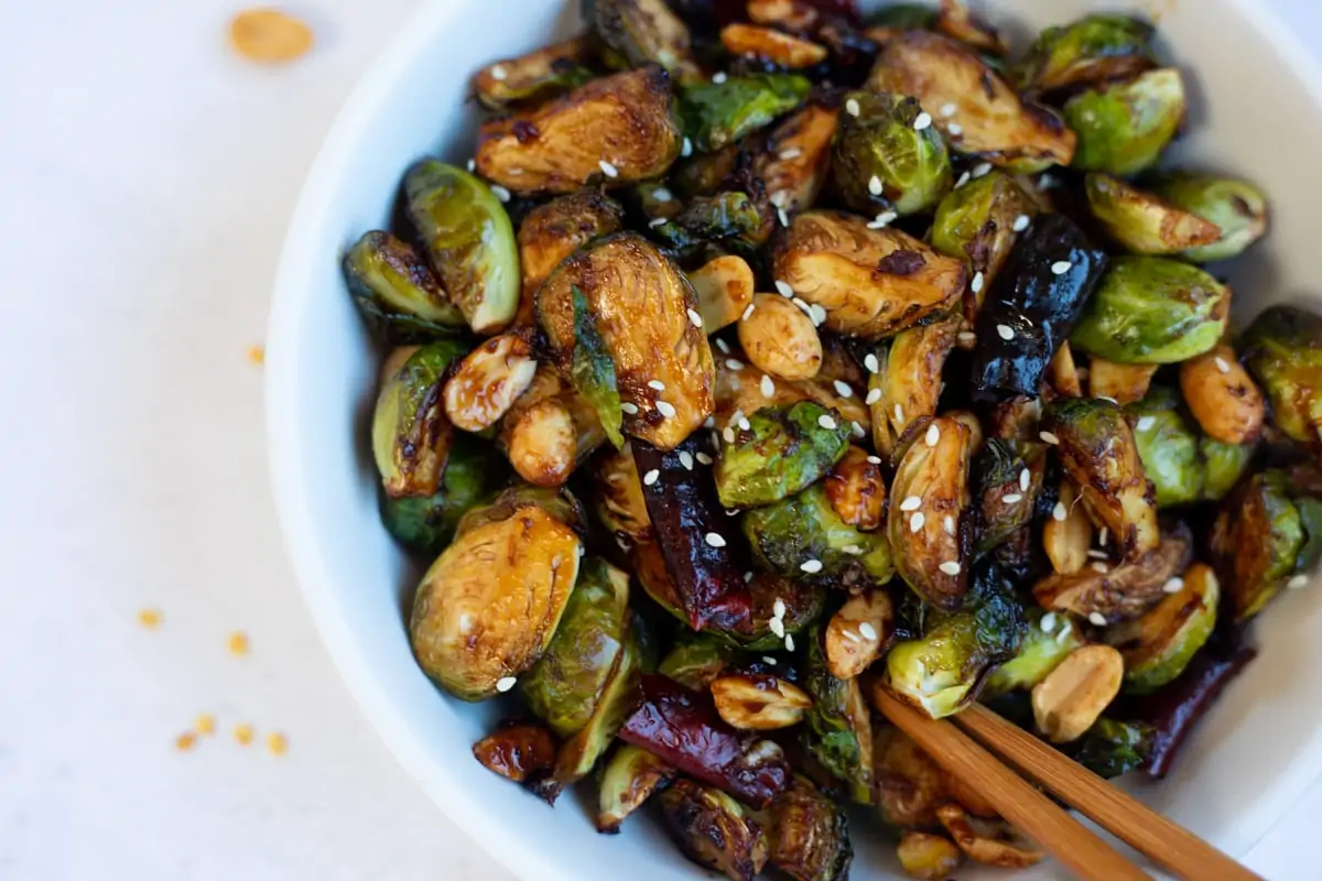 Kung pao brussels sprouts in a bowl topped with sesame seeds