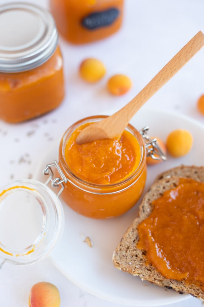 Apricot jam in glass jars and spread on bread 