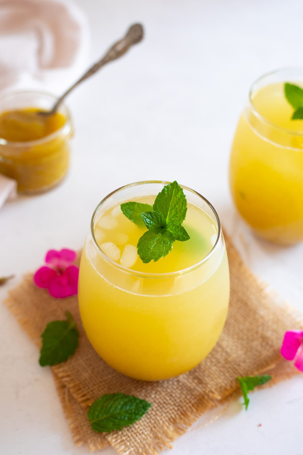Raw mango drink (aam panna) served in two glasses with the pulp in the a jar. 