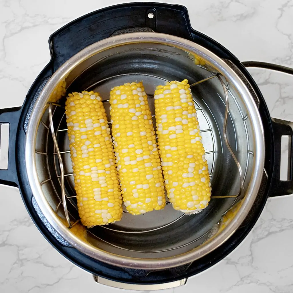 corn on the cob being cooked in the instant pot