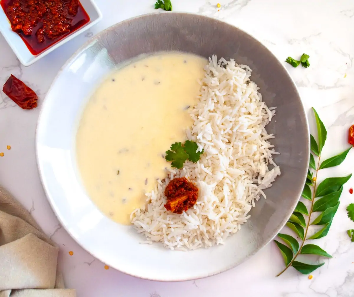 Gujarati kadhi served with rice and pickle in a bowl