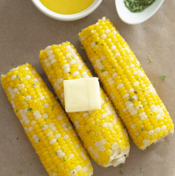 Corn on the cob slathered with butter and garnished with parsley