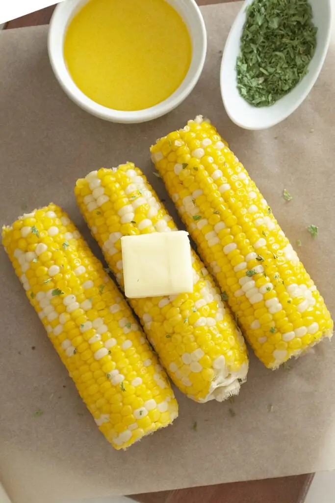 Corn on the cob slathered with butter and garnished with parsley