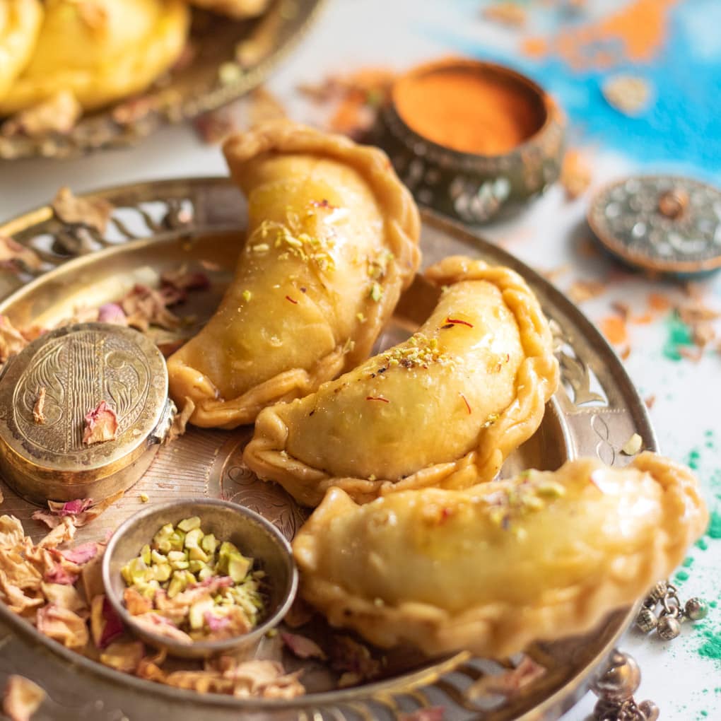 Mawa gujiya in a pretty place with holi colors spread around