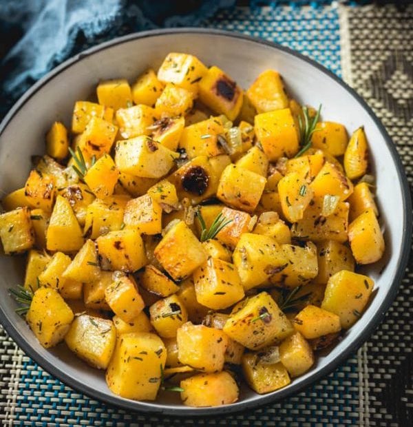 Roasted Rutabaga garnished with rosemary and onions in a serving bowl