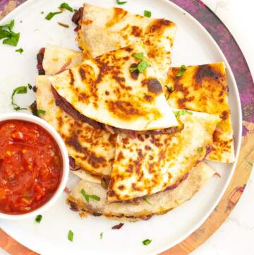 Loaded black bean veggie quesadilla in a plate with salsa