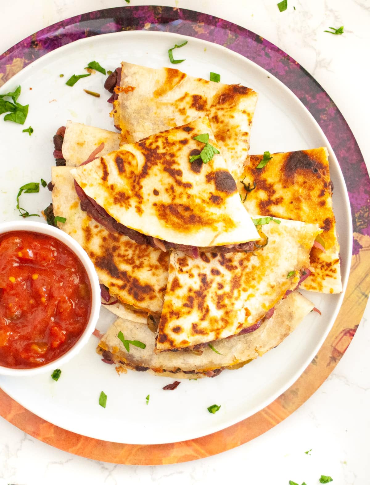 Loaded black bean veggie quesadilla in a plate with salsa 