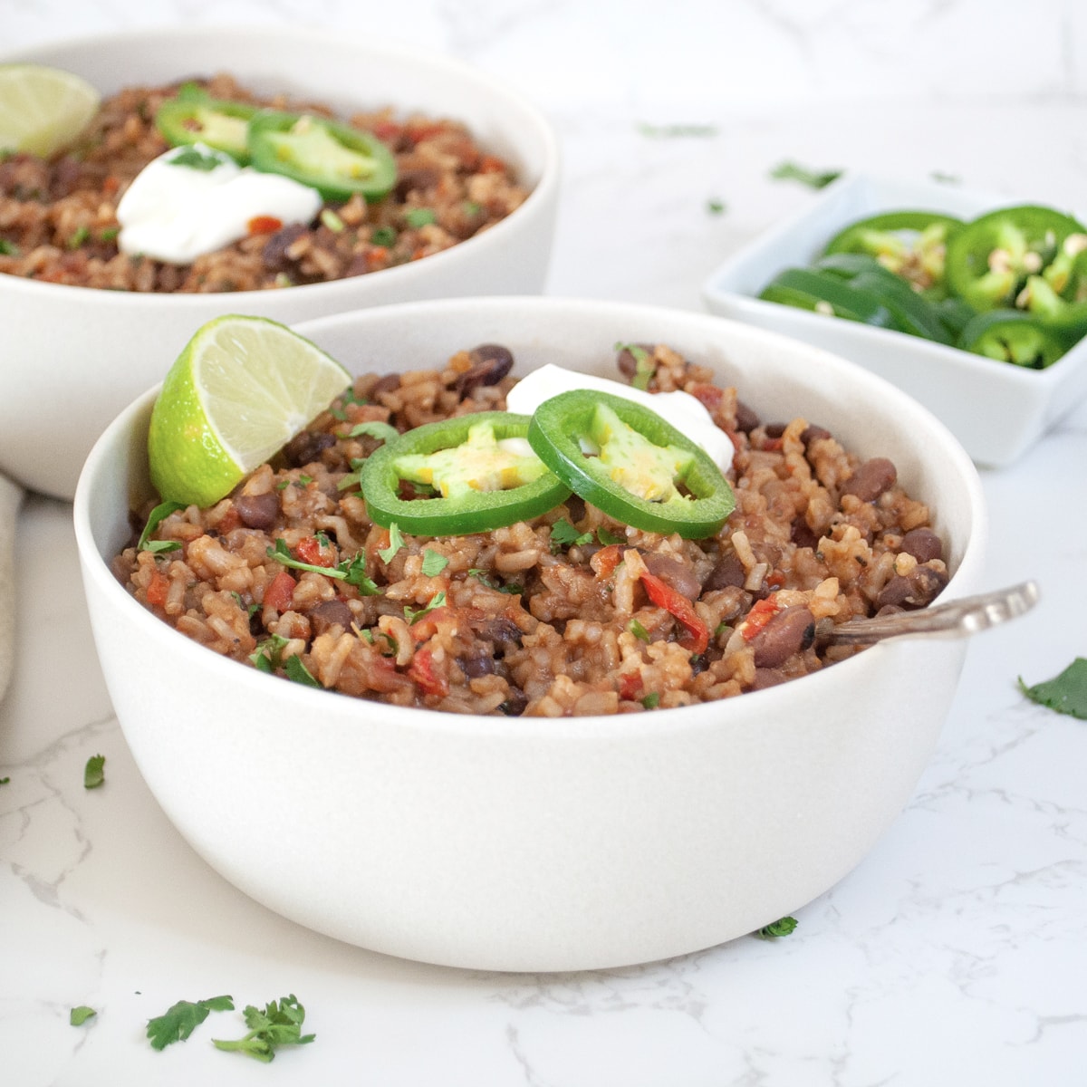 Rice and beans served in a bowl garnished with sour cream and jalapeños