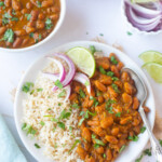 Kidney beans curry with rice (rajma chawal) in a plate garnished with cilantro, lime and onions