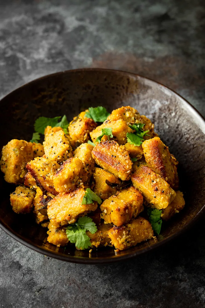 Dudhi muthia in a bowl garnished with cilantro