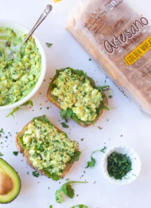 Avocado egg salad sandwich on a whole wheat bread topped with arugula