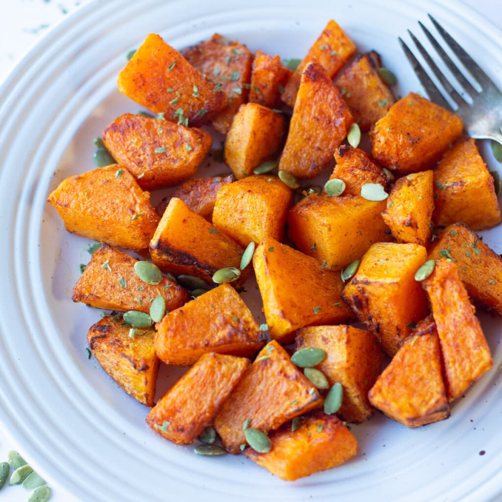 Air fryer roasted pumpkin in a plate topped with pumpkin seeds