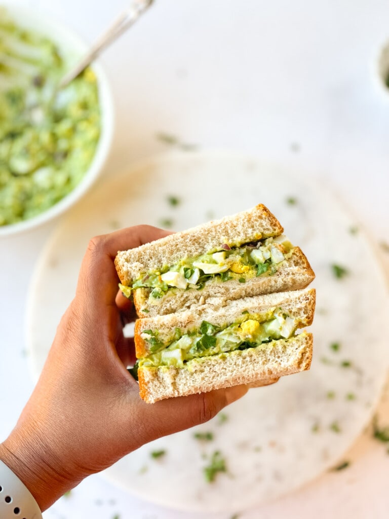 avocado egg salad sandwich in hand 