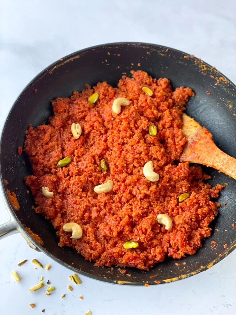 Gajar ka halwa (carrot pudding) in a large pan topped with nuts
