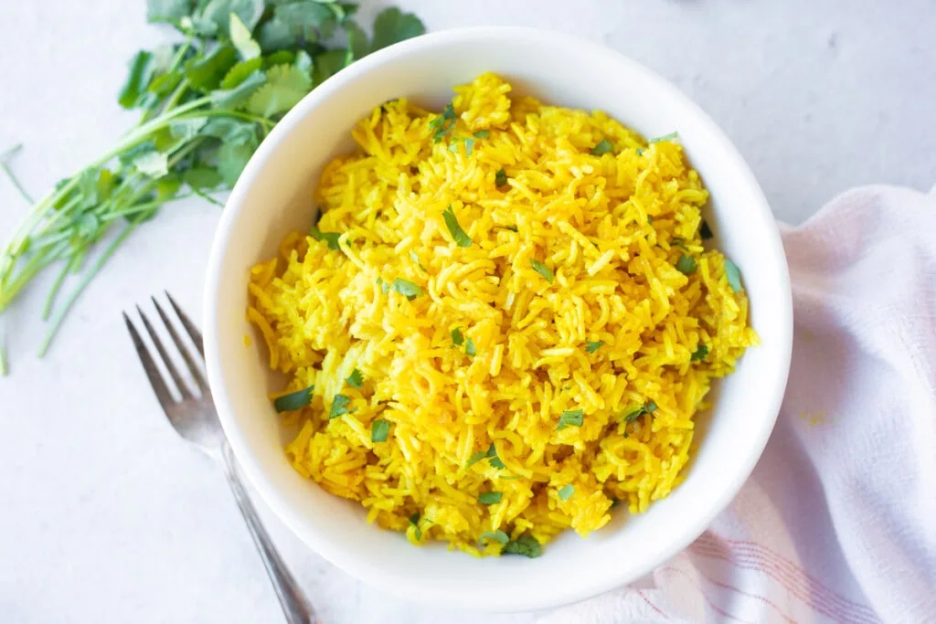 golden Turmeric rice in a bowl garnished with cilantro 