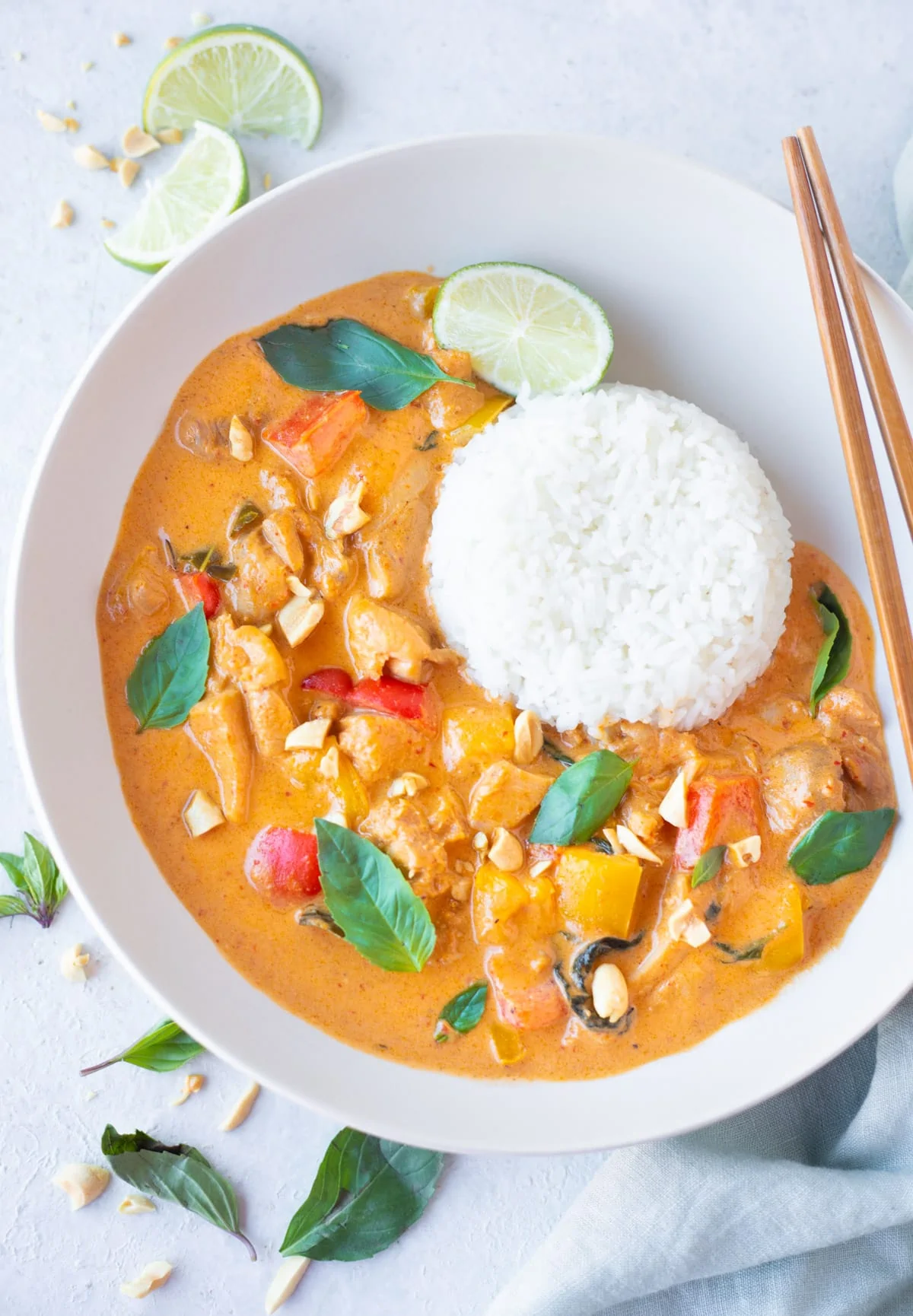 Panang Curry with chicken served in a bowl with jasmine rice and garnished with thai basil leaves 